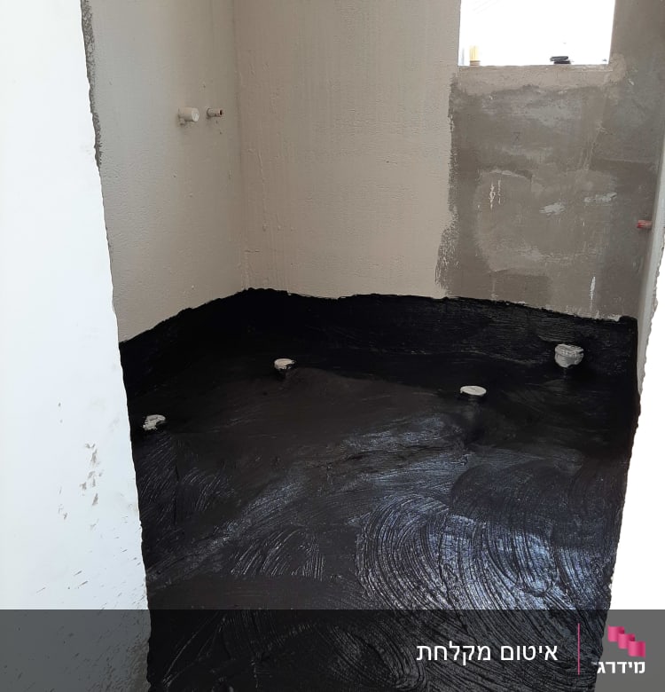 רצפה אטומה בחומר שחור עם צינורות בולטים